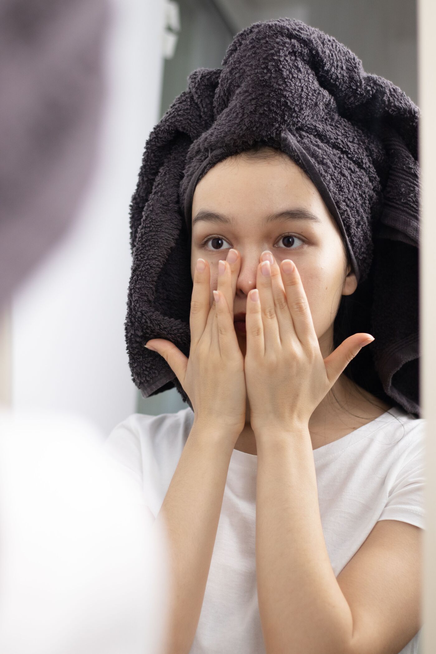 Jeune femme appliquant délicatement son soin du bout des doigts devant le miroir